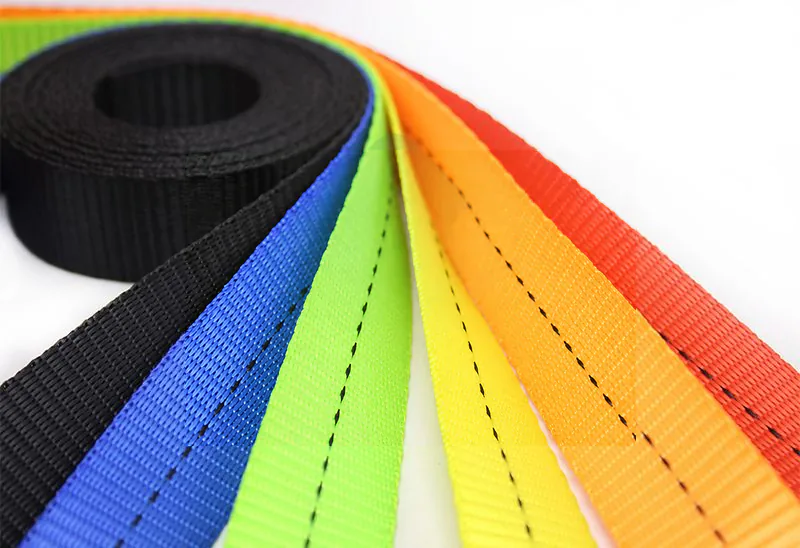 Fan of coloured polyester webbings reveals weave texture, edge finish and contrasting tracer stitches
