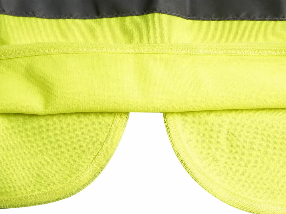 Curved high-visibility vest bound edge beside reflective tape and folded hem