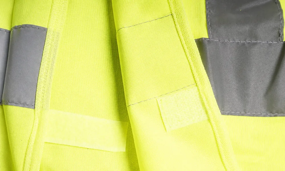 High-visibility vest hook-and-loop fastening beside reflective tape and parallel stitch lines