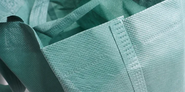 Nonwoven tote fabric with bound edge, handle web and double stitch rows shown in close view