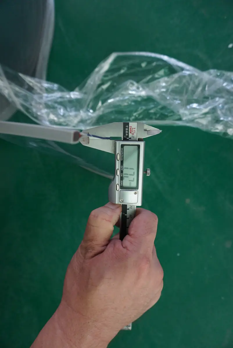 Caliper applied to transparent flexible panel material to illustrate a controlled measurement method.