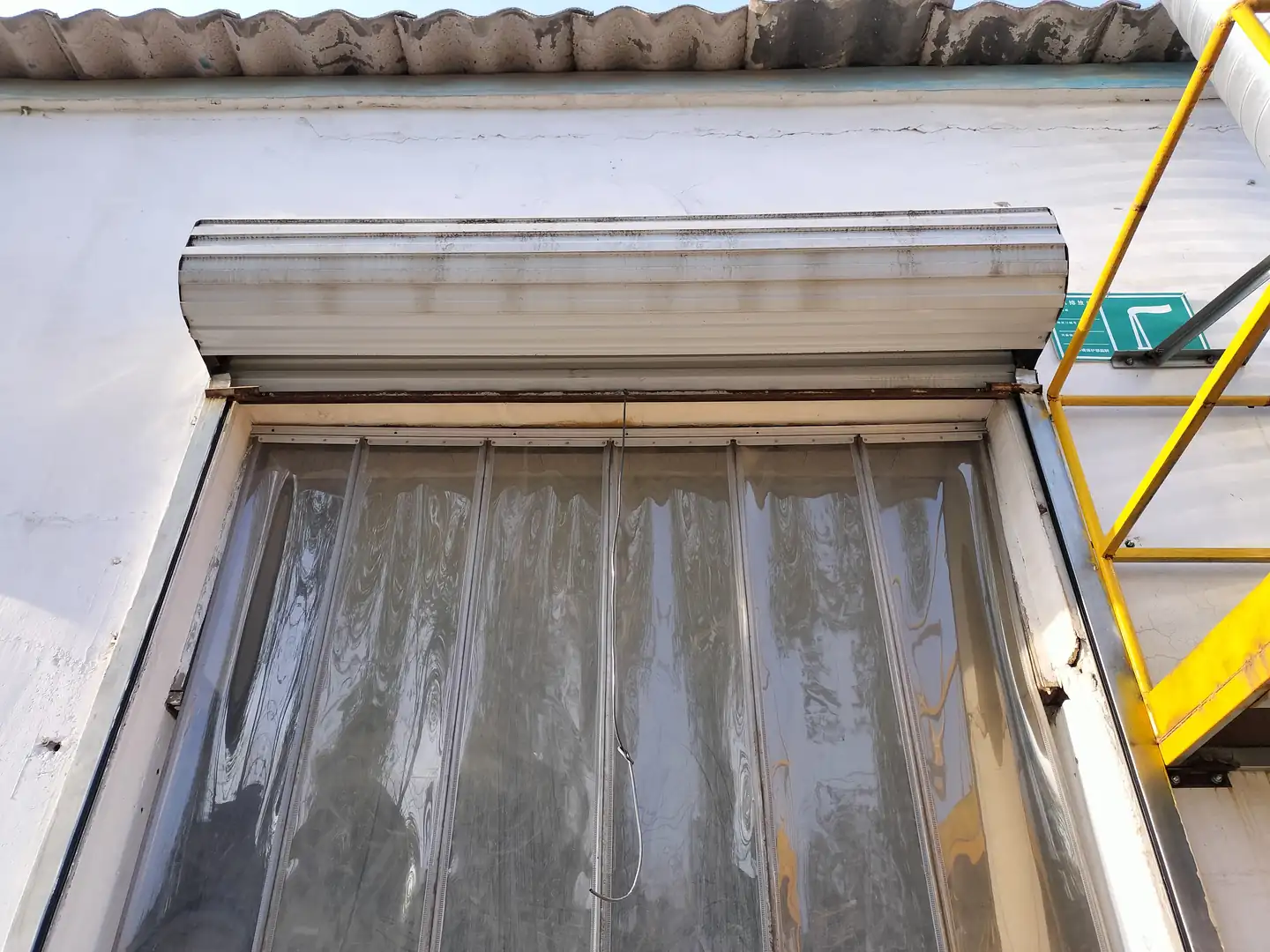 Exterior industrial doorway with a header, side frame and transparent flexible panels.