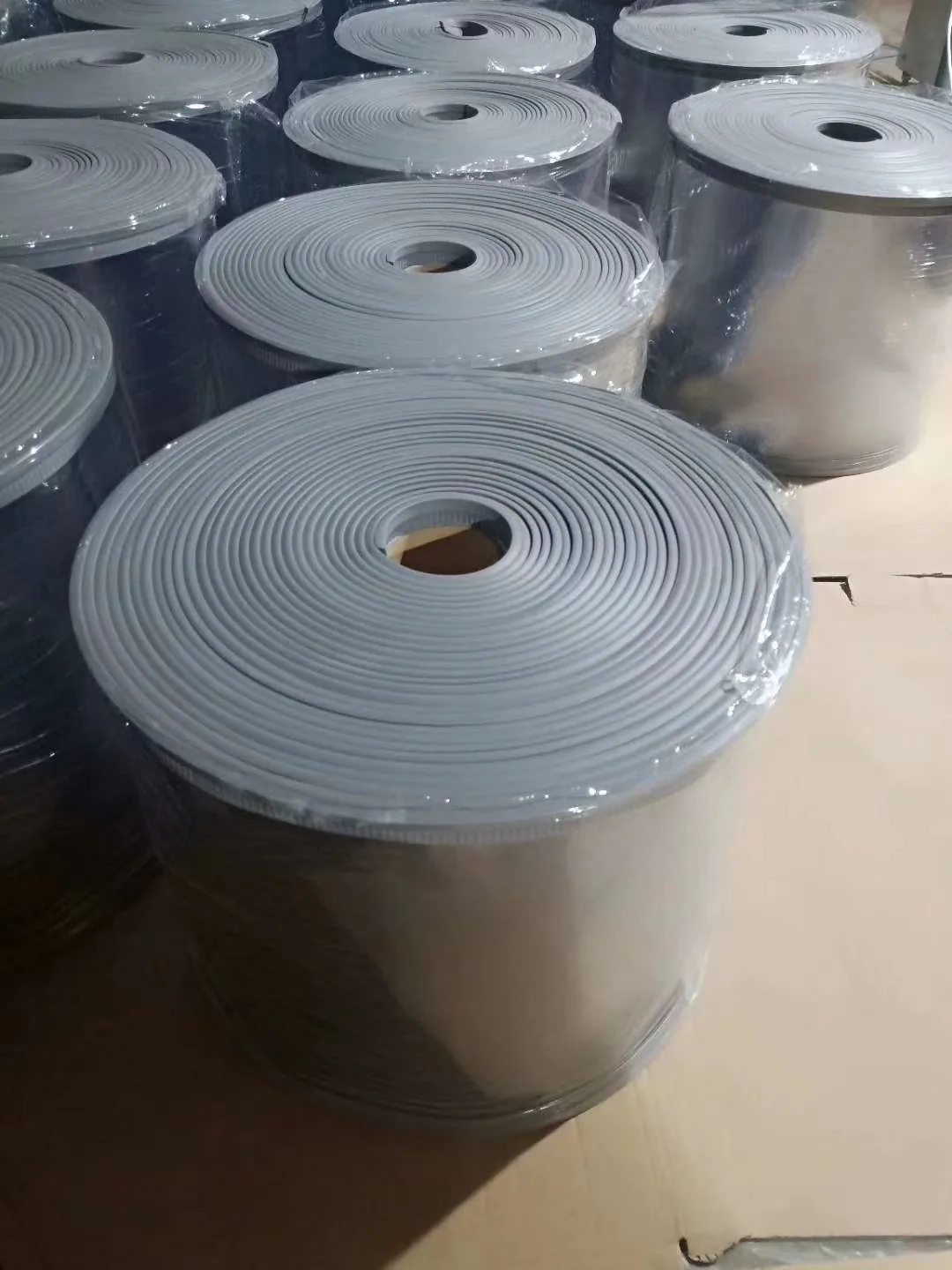 Multiple wrapped clear-panel rolls with gray edge carriers staged together on a plain surface.