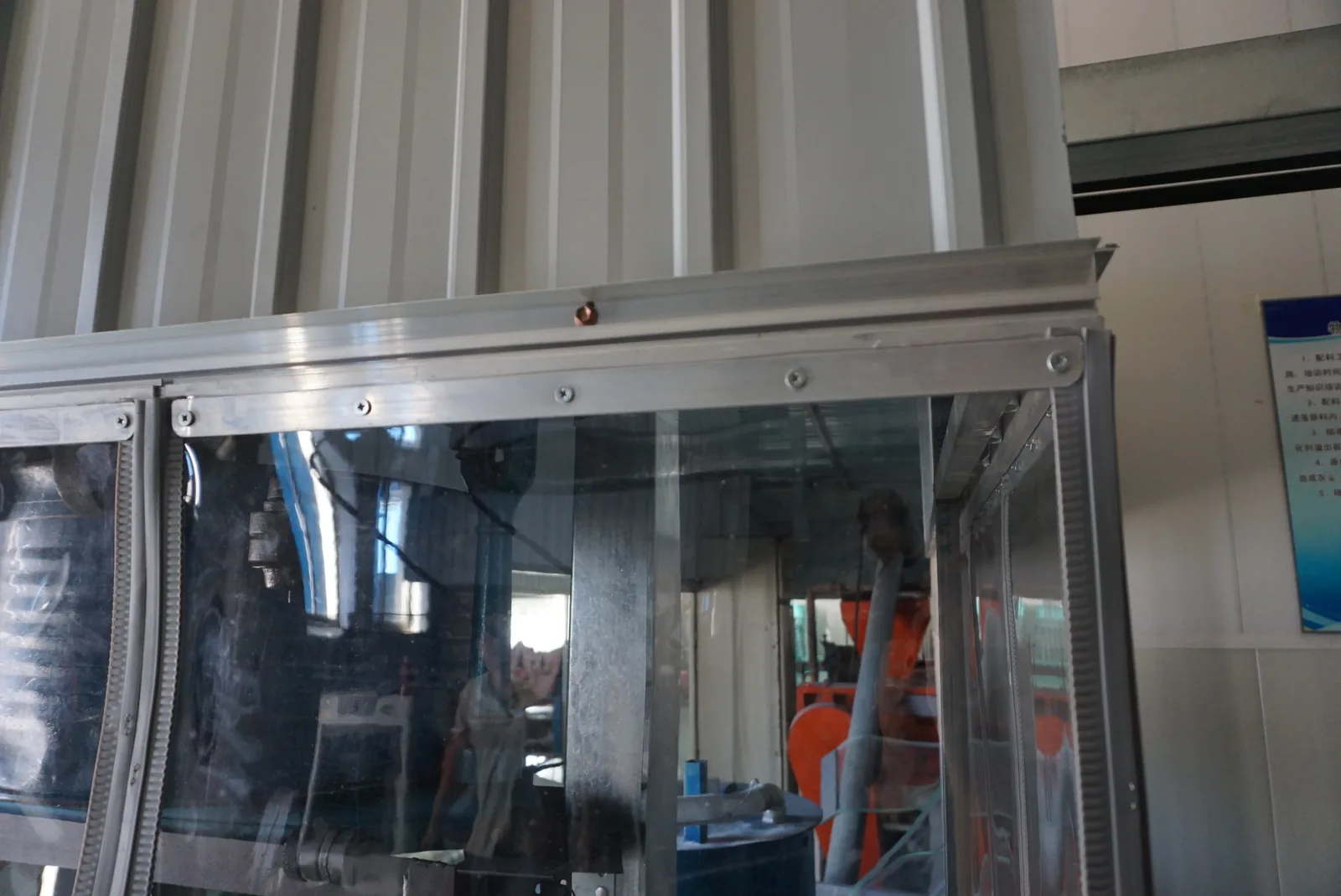Installed top rail, fasteners and clear hanging panels at an industrial enclosure corner.